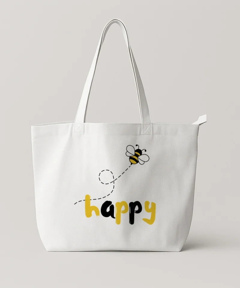 White canvas tote bag featuring a cheerful bee illustration and the word “happy.”
