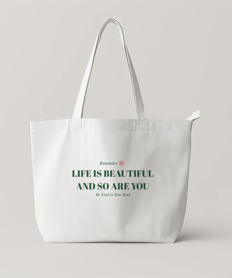 White tote bag with the inspirational text “Life Is Beautiful and So Are You” and subtle accent graphic.
