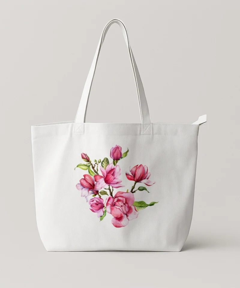 White tote bag featuring a central watercolor illustration of pink magnolias and green leaves.